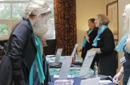 KDM Events - Conference Management Company - Three ladies standing behind a conference welcome check in desk'